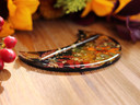 Side view of crescent-shaped Autumn Alchemy tarot card holder showing its glossy resin finish and embedded fall botanicals.