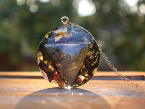 Handcrafted 14k gold-filled round pendant infused with a triangle golden rutile quartz stone, green tea, and hibiscus herbs in eco resin. Hanging from a 16" 14k gold-filled chain. Handcrafted 14k gold-filled round pendant infused with a triangle golden rutile quartz stone, green tea, and hibiscus herbs in eco resin. Hanging from a 16" 14k gold-filled chain.
