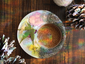 "Handcrafted floral and crystal-infused candle holder with a cork insert, featuring pressed yellow, pink, and green botanical details on a round resin base." "Handcrafted floral and crystal-infused candle holder with a cork insert, featuring pressed yellow, pink, and green botanical details on a round resin base."
