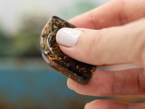 Stillness Drop Grounding Stone displayed in hand with thumb rubbing the smooth center divot.