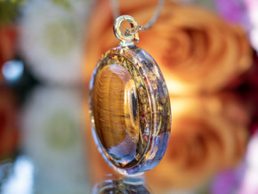 Side view of round Tiger’s Eye pendant showing layered eco resin and gold inset frame