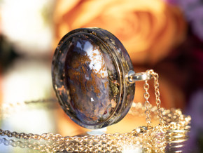 Side view of moss agate tea-infused pendant showing layered eco resin and botanical infusion