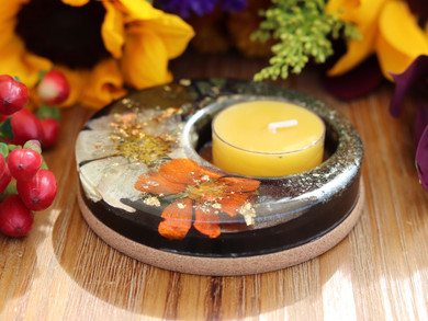 Close view of Autumn Alchemy candle holder featuring pressed fall flowers, metallic leaf and a golden beeswax tealight.