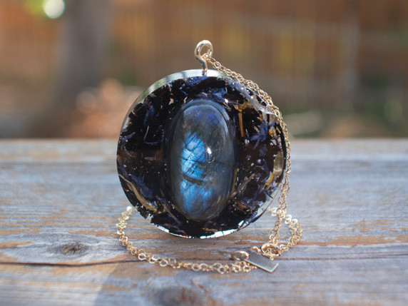 Handcrafted 14k gold-filled round pendant infused with a blue flash, labradorite stone, black tea, and blue cornflower petals in eco resin. Hanging from a 16" 14k gold-filled chain.