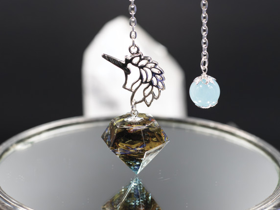 Close-up of Unicorn Magic Pendulum hanging from a sterling silver chain over a mirror