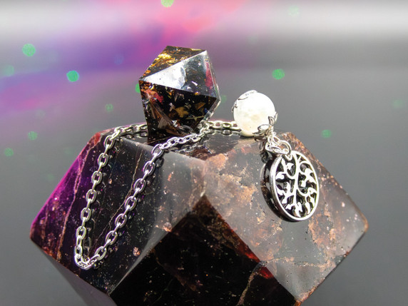 Oracle Moon pendulum with moonstone bead and silver leaves charm displayed on a crystal background under ethereal pink and green light.