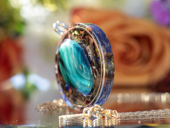 Side profile of round malachite pendant showing layered resin and gold inset frame