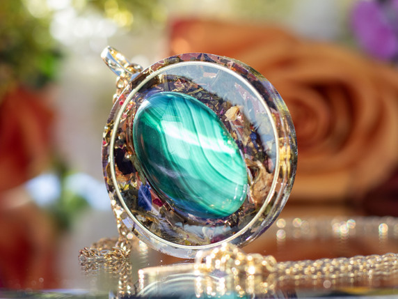 Close-up of I AM Transformed pendant featuring AAA malachite set in gold ring with tea botanicals in resin