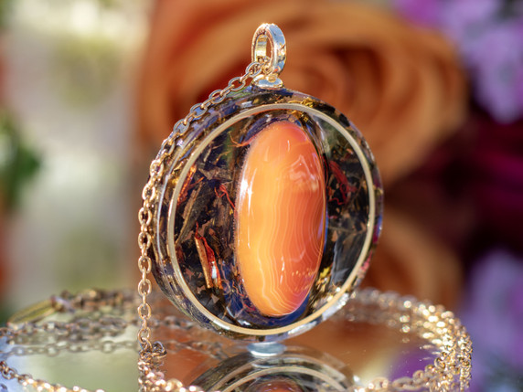 Side view of round agate pendant showing layered eco resin and botanical infusion