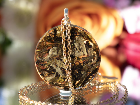Back view of green tea leaves suspended in clear resin within circular pendant