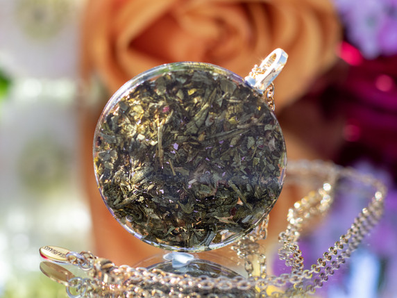 Back view of green tea leaves suspended in clear resin within circular pendant