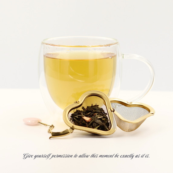 Brewed Mindful Green loose-leaf sencha green tea with a golden infusion and tea infuser.