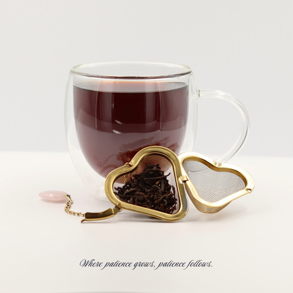 Brewed Winter Harvest aged pu’er tea with a heart-shaped loose-leaf tea infuser and deep mahogany tea liquor.