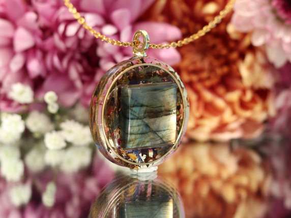 Angled view of AAA Green Labradorite pendant showing blue, green and gold flash surrounded by Mindful Green tea botanicals.