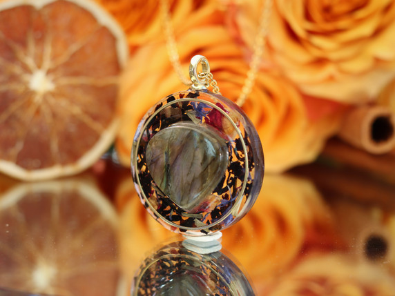Angled view of handmade purple labradorite necklace showing the heart-shaped gemstone, black tea botanicals and layered resin design.