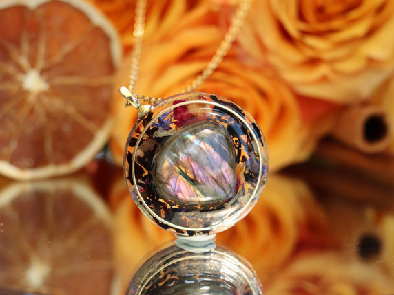 Purple labradorite pendant with vivid pink, violet and gold flash, surrounded by black tea and colorful botanicals in resin.
