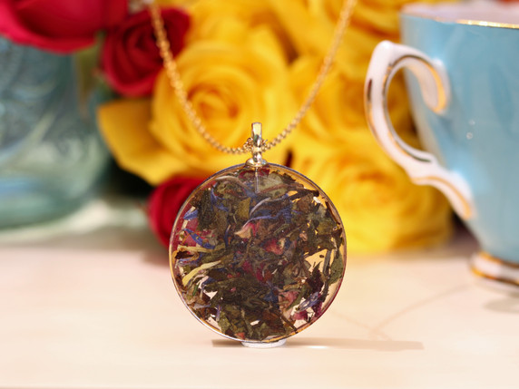 Reverse side of The Scribe pendant showing White Tea leaves and colorful botanicals preserved in clear resin