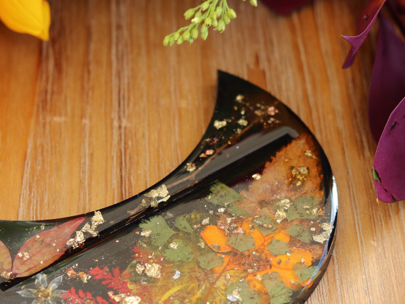 Close-up of Autumn Alchemy resin tarot card holder showing pressed orange flowers, autumn leaves and gold metallic details.