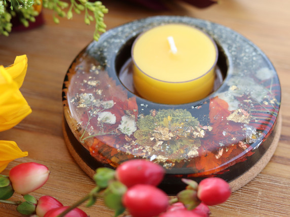 Close-up of botanical candle holder with yellow and red pressed blossoms, metallic leaf and Pyrite surrounding a beeswax tealight.
