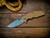 Jurassic-Slicer Hollow Ground-Magnacut-Battle Green Special Finish-Coyote G10-Light Blue Titanium Hardware-Scale sideJurassic-Slicer Hollow Ground-Magnacut-Battle Green Special Finish-Coyote G10-Light Blue Titanium Hardware-Scale Side