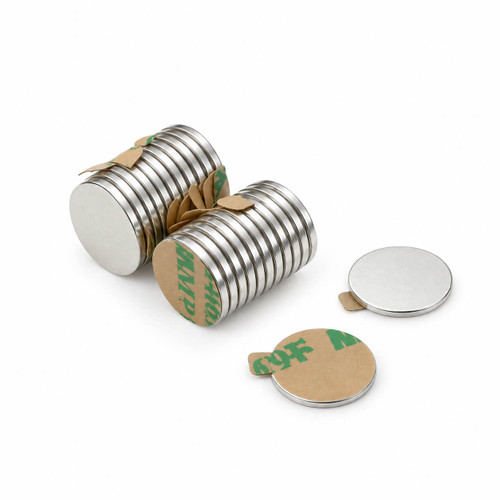 Self-adhesive silver disc magnets in two stacks with separate adhesive-backed magnets on a white background