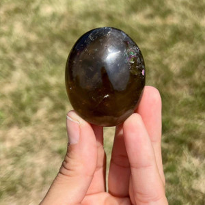 Smoky Quartz Palm Stone held between fingers, a deep brown polished oval