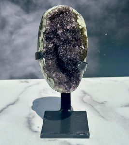 Uruguayan Black Amethyst cluster on a black iron stand, with violet-black druzy framed by a green and cream agate rim