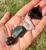 Four raw Yule crystals lined up in hand: Black Obsidian, Clear Quartz, Bloodstone and Garnet