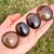 Four Smoky Quartz Palm Stones in an open palm in shades from light tan to deep brown