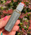 Dragon's Blood Oil roller bottle held in hand outdoors, showing its grey label