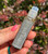 Evil Eye Protection Oil roller bottle held in hand outdoors, displaying its label