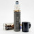 Evil Eye Protection Oil roller bottle standing beside its cap and dried botanicals on a dark background
