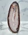 White quartz and agate slab, front polished, standing upright on a black metal stand against white marble