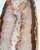 Close-up of white and pink quartz crystal with orange agate banding beside the raw tan rind