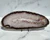 White quartz and agate slab shown horizontally on a black metal stand against white marble