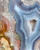 Detail of rust-red agate banding with white crystal fans and green mineral specks