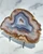 Banded blue agate slab shown at an angle on its black metal stand against white marble