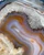 Detail of the gray druzy patch surrounded by swirling orange and blue-gray agate bands