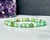 Variscite elastic bracelet with 6mm mint green beads on a white surface in front of an amethyst cluster