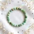 Variscite elastic bracelet flat lay on white fabric with dried baby's breath and rainbow light