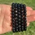 Close up of Hypersthene bracelets held in a palm showing the silver and bronze shimmer in the black beads