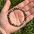 Dendritic Agate 6mm beaded bracelet held in an open palm in sunlight over grass