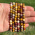 Hand holding a stack of Mookaite elastic bracelets in both 6mm and 8mm bead sizes