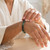 Woman in a cream robe adjusting a Seraphinite beaded bracelet on her wrist