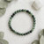 Seraphinite elastic bracelet flat lay on white fabric with a selenite stick and eucalyptus