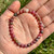 Close up of Rhodonite beads in hand showing the pink, cream and black patterning