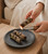 Lighting a Yerba Santa cleansing bundle over a dark stone dish holding two more bundles