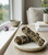 Two Yerba Santa cleansing bundles on a speckled ceramic dish on a windowsill beside amethyst