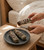 Lighting a Yerba Santa, Lavender & Blue Sage cleansing bundle over a dark stone dish holding two more bundles