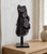 Black Amethyst cluster on its iron stand displayed on a wooden console beside a cream vase